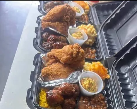 Rows of fried chicken plates with sides, packed in to-go containers