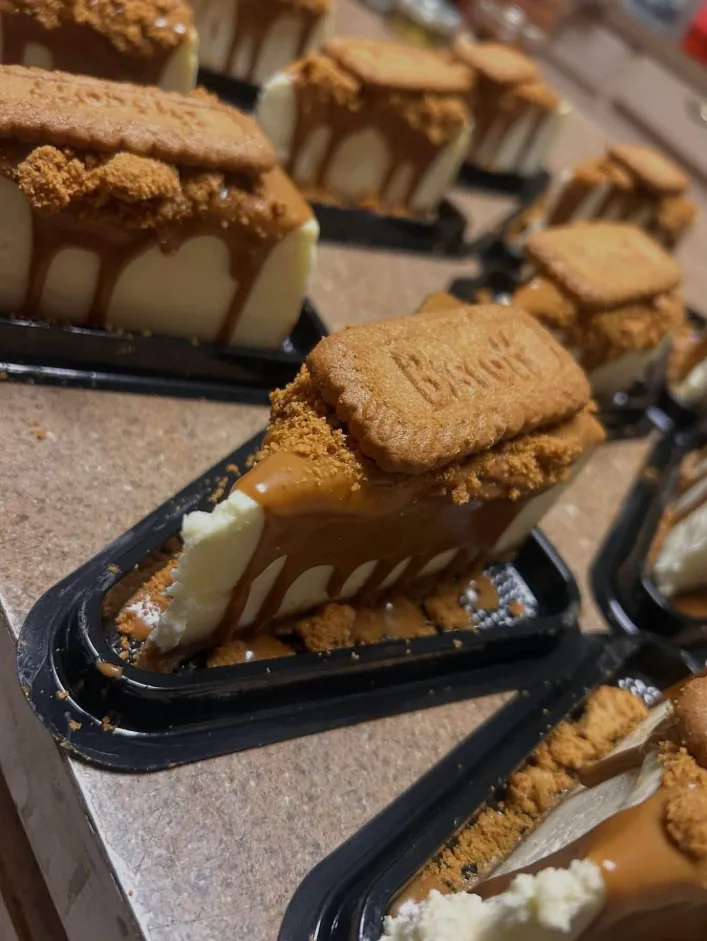 Slices of Biscoff cheesecake with caramel drizzle, lined up in trays