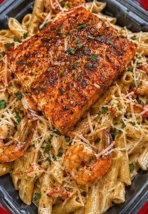 Seafood penne pasta with shrimp, topped with seasoned salmon